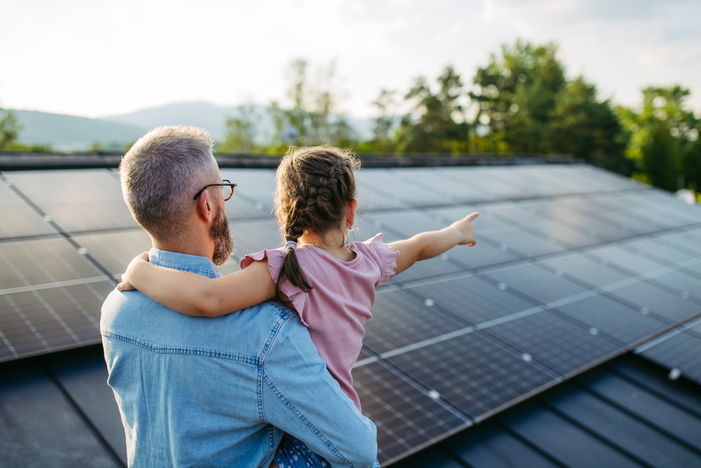Rear,View,Of,Dad,With,Girl,On,Roof,With,Solar